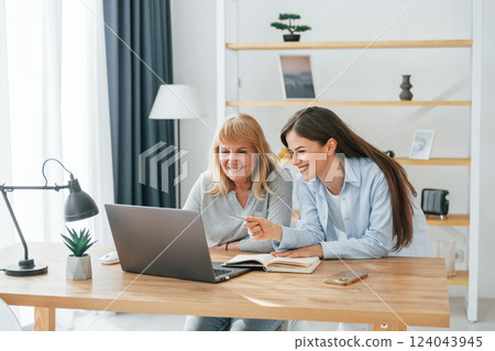 Learning how to use modern technologies. Smartphone and laptop. Mother and daughter is together at home 124043945