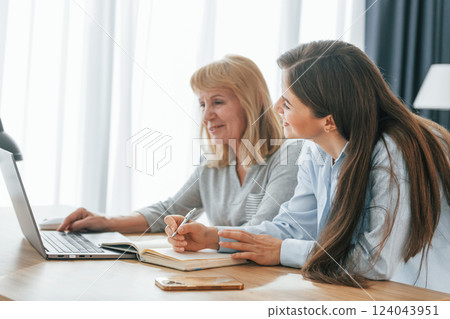 Sitting by table with laptop. Mother and daughter is together at home 124043951