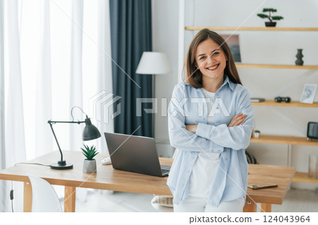 Standing with arms crossed. Young beautiful woman is home alone in domestic room 124043964