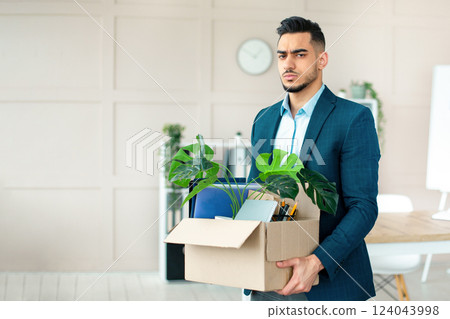 Economic crisis concept. Unhappy Arab man holding personal belongings after being fired at office. Unemployed Eastern guy in formal wear feeling depressed after losing his job 124043998