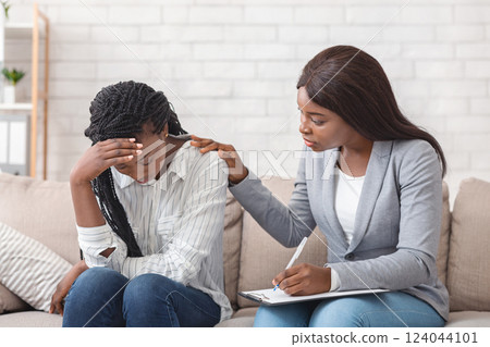 Female psychologist consoling depressed black woman at therapy session in office, supporting her to share problems Female psychologist consoling depressed black woman at therapy session in office, supporting her to share problems 124044101
