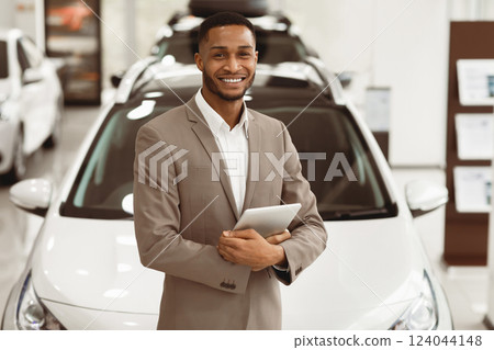 Smiling Car Dealer Standing Near Luxury Automobile Holding Folder Working In Auto Selling Showroom. Vehicle Dealership Concept Smiling Car Dealer Standing Near Luxury Automobile Holding Folder Working In Auto Selling Showroom. Vehicle Dealership Concept 124044148
