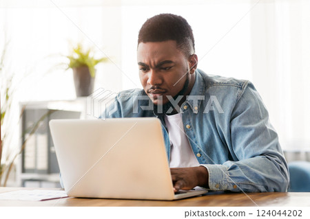 Important task. Focused african american employee working on laptop in office, free space Important task. Focused african american employee working on laptop in office, free space 124044202