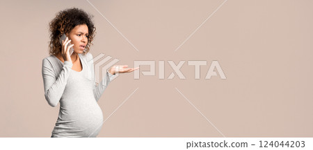 Worried afro pregnant woman talking on phone, having serious conversation, grey background Worried afro pregnant woman talking on phone, having serious conversation, grey background 124044203