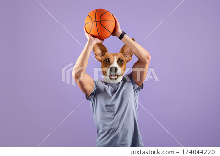 A man with a dog's head is holding a basketball above his head. He is wearing a gray t-shirt and is standing against a purple background. A man with a dog's head is holding a basketball above his head. He is wearing a gray t-shirt and is standing against a purple background. 124044220