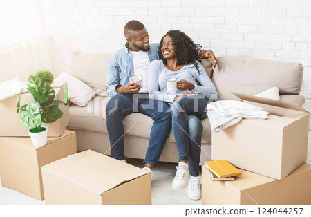 Place together. Happy bblack couple taking break, drinking tea, unpacking on moving day, copy space Place together. Happy bblack couple taking break, drinking tea, unpacking on moving day, copy space 124044257