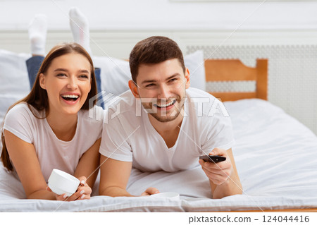Weekend Leisure. Happy Couple Watching TV Relaxing Together Lying In Bed Indoor. Selective Focus, Free Space 124044416