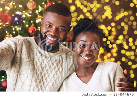 Xmas selfie. Happy black couple taking self-portrait with Christmas tree on background, celebrating holidays. Xmas selfie. Happy black couple taking self-portrait with Christmas tree on background, celebrating holidays. 124044676