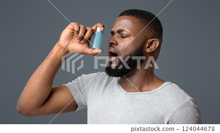 Picture of a young black man having an asthma attack, using inhaler over white background Picture of a young black man having an asthma attack, using inhaler over white background 124044678