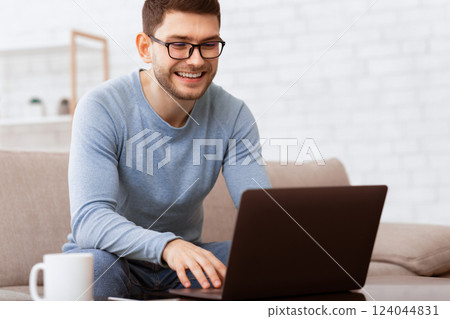 Freelance Career. Smiling Freelancer Guy Using Laptop Working Online Sitting On Sofa At Home. Selective Focus Freelance Career. Smiling Freelancer Guy Using Laptop Working Online Sitting On Sofa At Home. Selective Focus 124044831