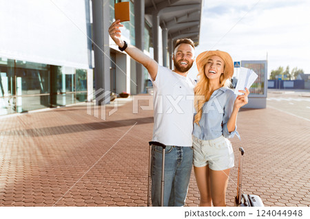 Travel concept. Loving couple going on vacation and holding tickets against airport building 124044948