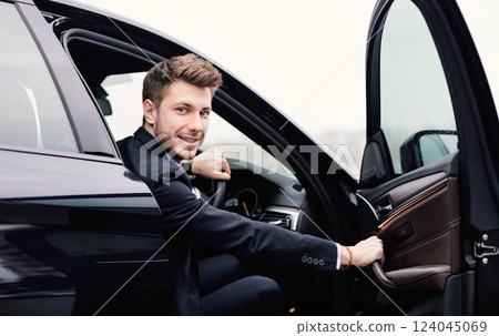 Confident Chauffeur. Guy in suit sitting in driver's seat, getting in his car at downtown area, closing the door 124045069