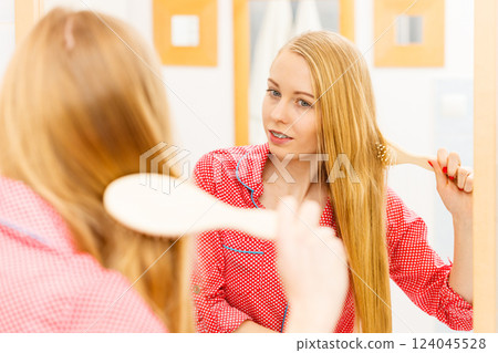 Woman brushing her long hair in bathroom 124045528