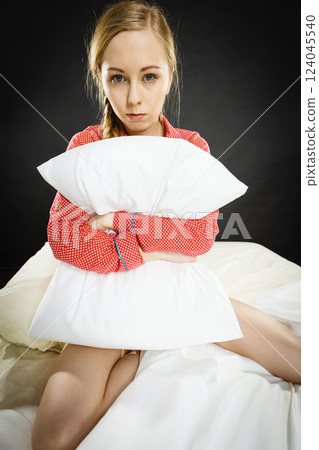 Sad depressed girl in bed gripping pillow 124045540