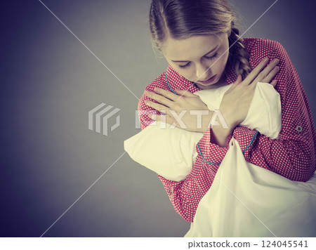 Sad depressed girl in bed gripping pillow 124045541