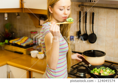 Woman cooking stir fry frozen vegetable on pan 124045574