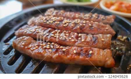 Delicious grilled meat with sesame seeds cooked on a hot grill in a Korean barbecue 124045626