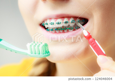 Girl with teeth braces using interdental and traditional brush 124046004