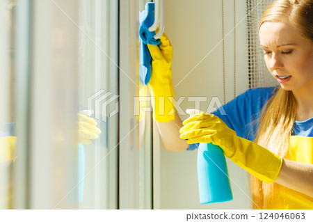 Girl cleaning window at home using detergent rag Girl cleaning window at home using detergent rag 124046063