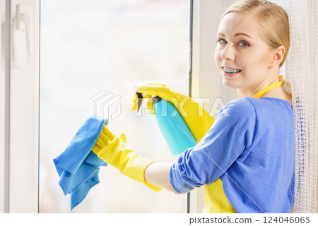 Woman cleaning window at home Woman cleaning window at home 124046065