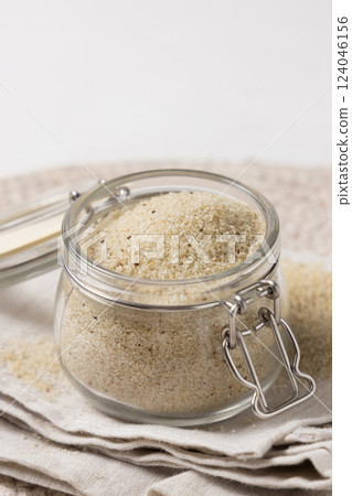 Jar of raw uncooked fonio seeds on gray napkin closeup. African pseudocereal. Healthy food concept 124046156