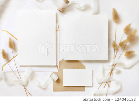 Cards and envelopes near silk ribbons and dried hare's tail grass top view on white, wedding mockup Cards and envelopes near silk ribbons and dried hare's tail grass top view on white, wedding mockup 124046158