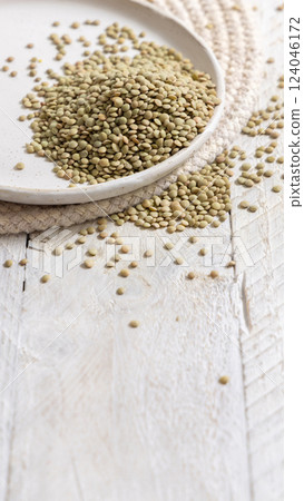 Plate full of dried raw green lentils on white table closeup. Traditional mediterranean legume Plate full of dried raw green lentils on white table closeup. Traditional mediterranean legume 124046172