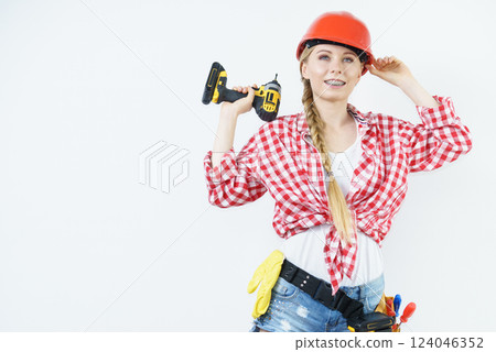 Woman wearing helmet using drill 124046352