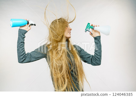 Female messy long hair holds spray bottle 124046385