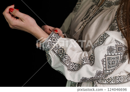 Close-up of a Woman Adjusting a Sleeve on Traditional White Embroidered Garment with Intricate Patterns Close-up of a Woman Adjusting a Sleeve on Traditional White Embroidered Garment with Intricate Patterns 124046696