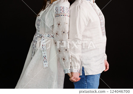 Couple Holding Hands Wearing Traditional White Embroidered Garments Against Black Background Couple Holding Hands Wearing Traditional White Embroidered Garments Against Black Background 124046700