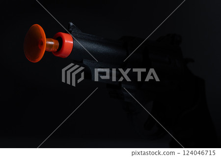 Dark Close-up View of Toy Gun Pointing with Orange Suction Cup Dart in Dramatic Lighting Dark Close-up View of Toy Gun Pointing with Orange Suction Cup Dart in Dramatic Lighting 124046715