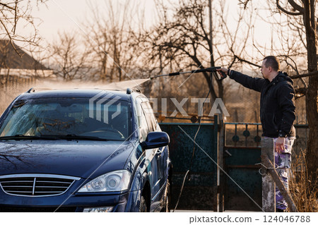 Man Washing Car Outdoors with High-Pressure Water Jet on Sunny Day 124046788