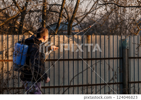 Man Spraying Pesticides on Metal Fence in Rural Area During Sunset Man Spraying Pesticides on Metal Fence in Rural Area During Sunset 124046823