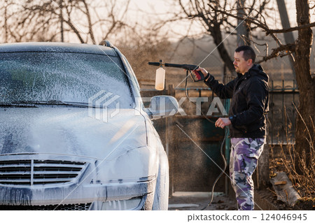 Man Washing Car With Pressure Washer Spraying Foam Outdoors During Sunny Day 124046945