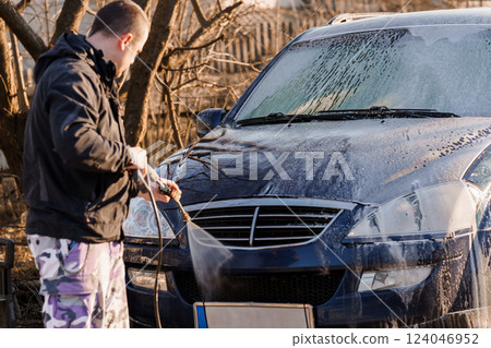 Man Cleaning Blue Car with High-Pressure Water Jet Outdoors on Sunny Day Man Cleaning Blue Car with High-Pressure Water Jet Outdoors on Sunny Day 124046952