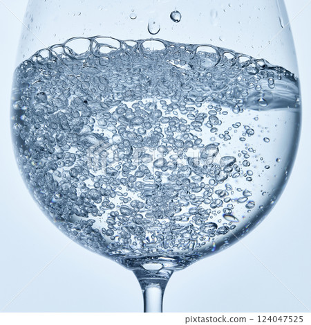Close-up photo of water filled with bubbles in clear stemmed glass against soft background. Mock up. Close-up photo of water filled with bubbles in clear stemmed glass against soft background. Mock up. 124047525