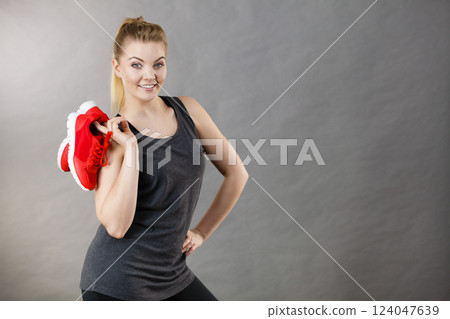 Happy woman presenting sportswear trainers shoes Happy woman presenting sportswear trainers shoes 124047639