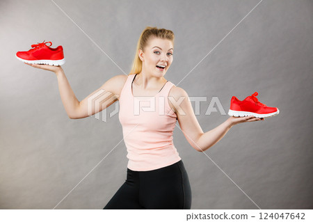 Happy woman presenting sportswear trainers shoes Happy woman presenting sportswear trainers shoes 124047642