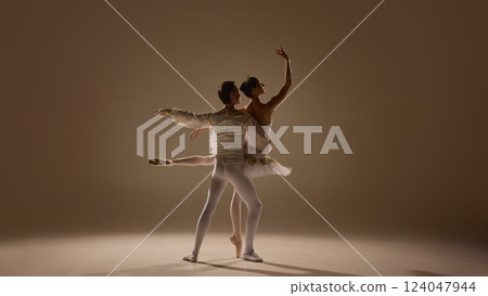 Ballet duet moves in perfect sync, ballerina extending with grace, partner supporting with strength, soft light emphasizing elegance. 124047944