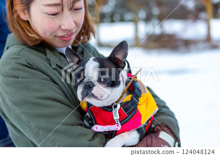 A woman and her dog playing in the snow A woman and her dog playing in the snow 124048124
