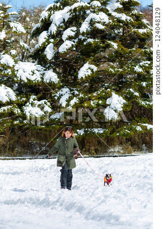 A woman and her dog playing in the snow A woman and her dog playing in the snow 124048129