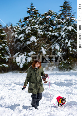 A woman and her dog playing in the snow 124048133