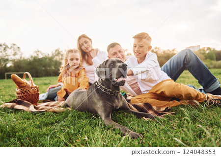 Laying down on the ground with dog. Family have weekend outdoors at summertime together Laying down on the ground with dog. Family have weekend outdoors at summertime together 124048353
