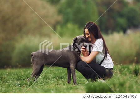 Embracing the pet. Young brunette is having a walk with her dog outdoors Embracing the pet. Young brunette is having a walk with her dog outdoors 124048408