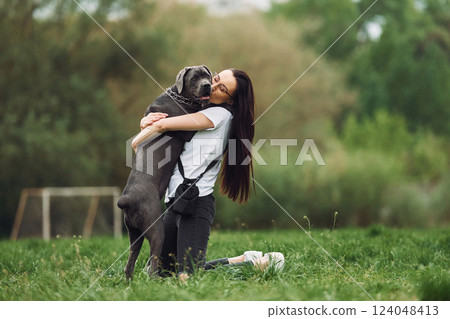 Hugs the pet. Young brunette is having a walk with her dog outdoors Hugs the pet. Young brunette is having a walk with her dog outdoors 124048413