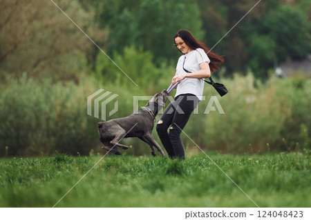 Active weekend time spending. Young brunette is having a walk with her dog outdoors Active weekend time spending. Young brunette is having a walk with her dog outdoors 124048423