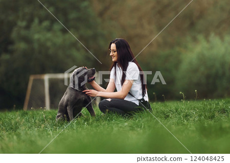 Young brunette is having a walk with her dog outdoors 124048425