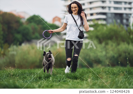 Active weekend time spending. Young brunette is having a walk with her dog outdoors 124048426