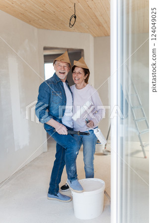 Portrait of senior couple having fun while painting walls with roller in new home. Portrait of senior couple having fun while painting walls with roller in new home. 124049025